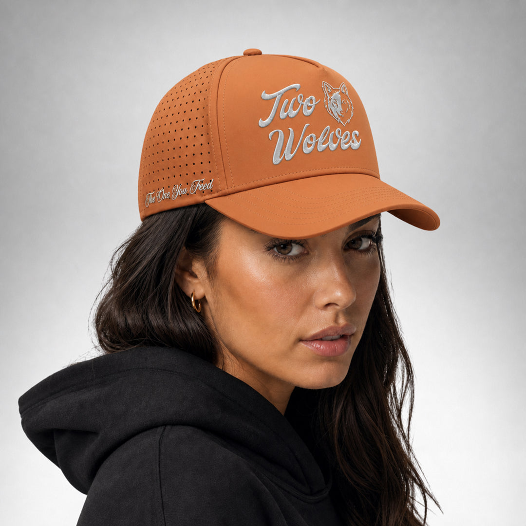 Rust orange cap with two wolves logo shown from the front worn by a female model.