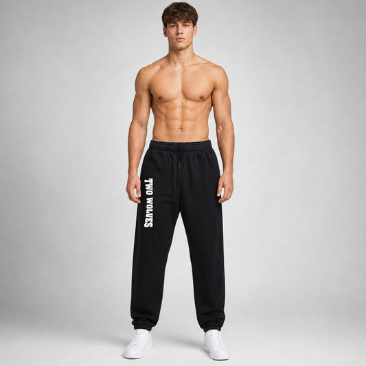 Black Two Wolves track pants with white logo on leg, worn by male model